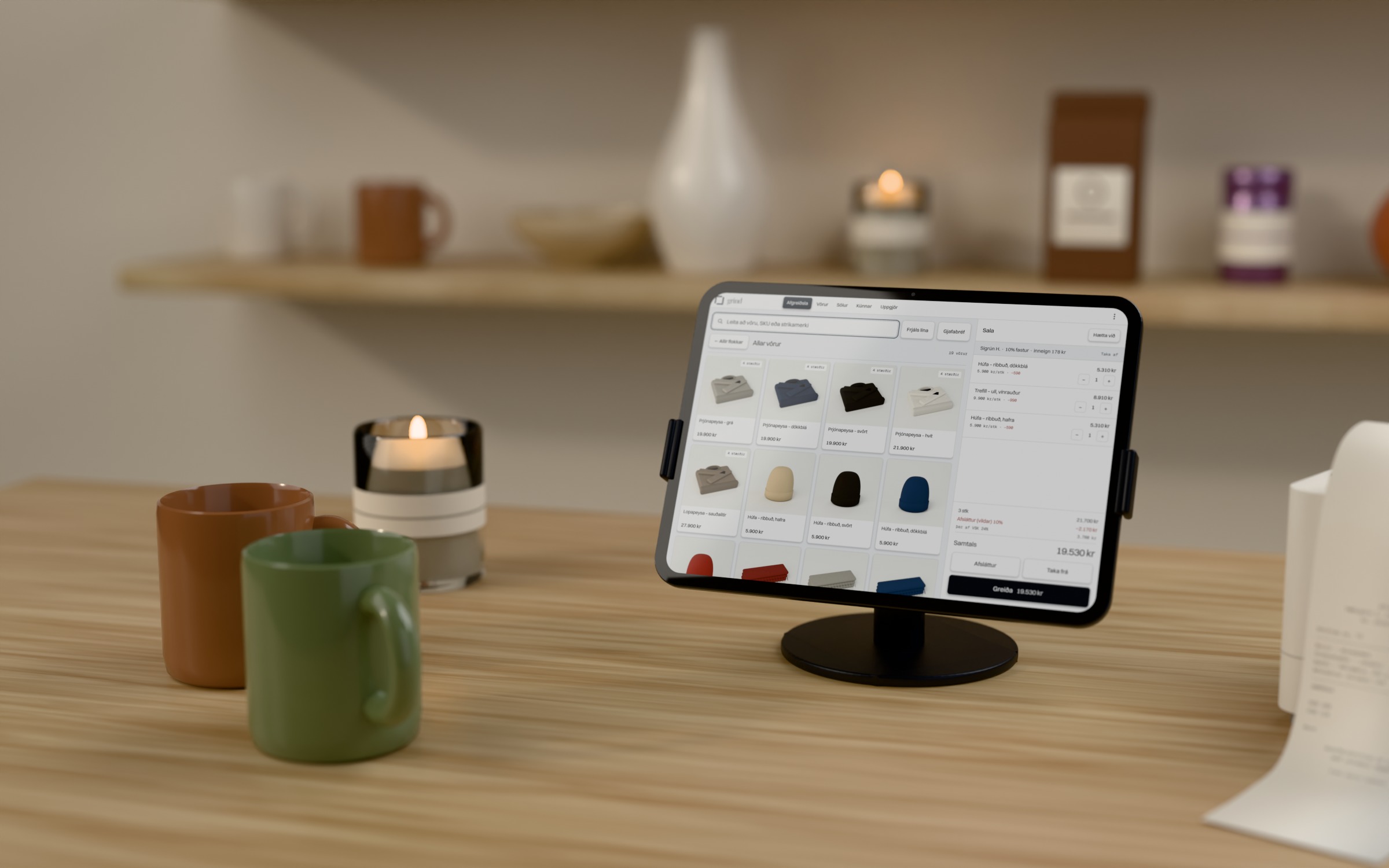grind kassi á iPad á standi, ljóst afgreiðsluviðmót á skjánum, á eikarborði í búð með logandi kertum og vörum á hillu.